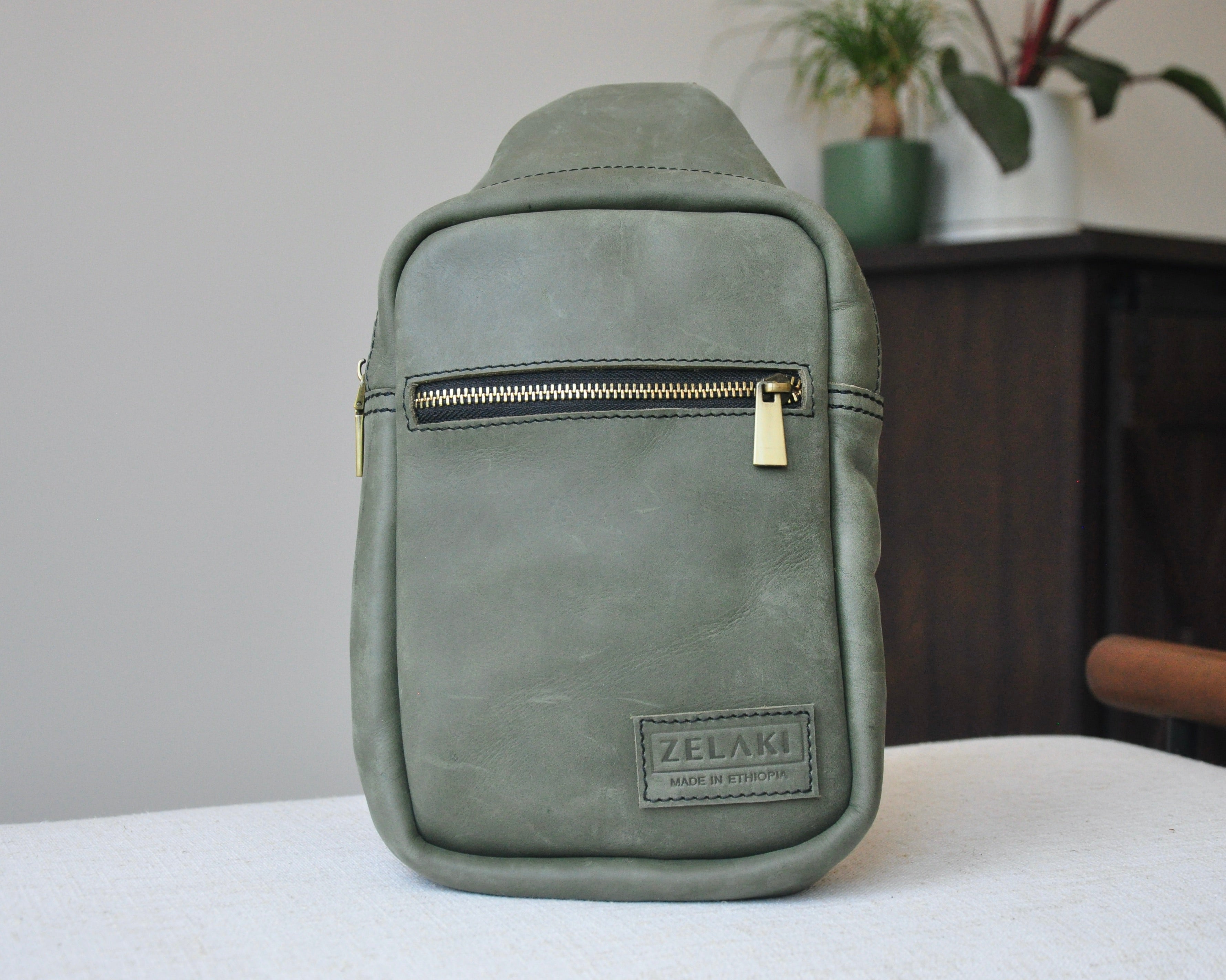 Full-grain Leather unisex sling bag with multiple pockets, designed for versatile wear as a crossbody on your front or back, small to medium size in olive