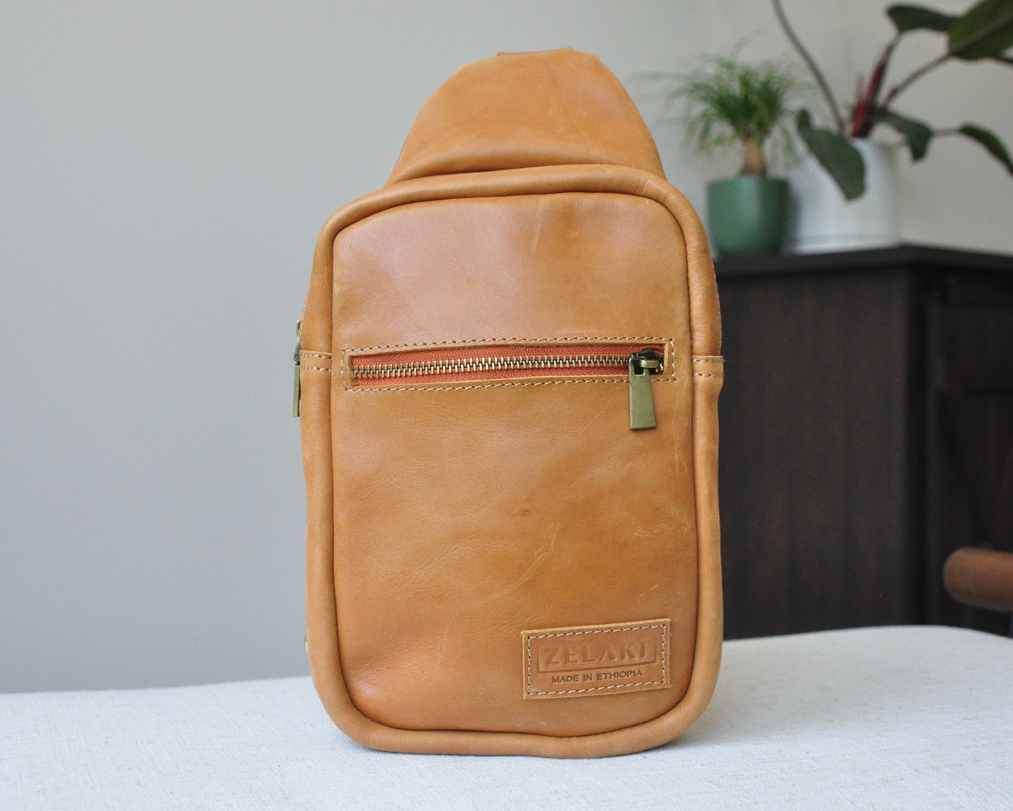 Full-grain Leather sling bag with multiple pockets, designed for versatile wear as a crossbody on your front or back, small to medium size in tan