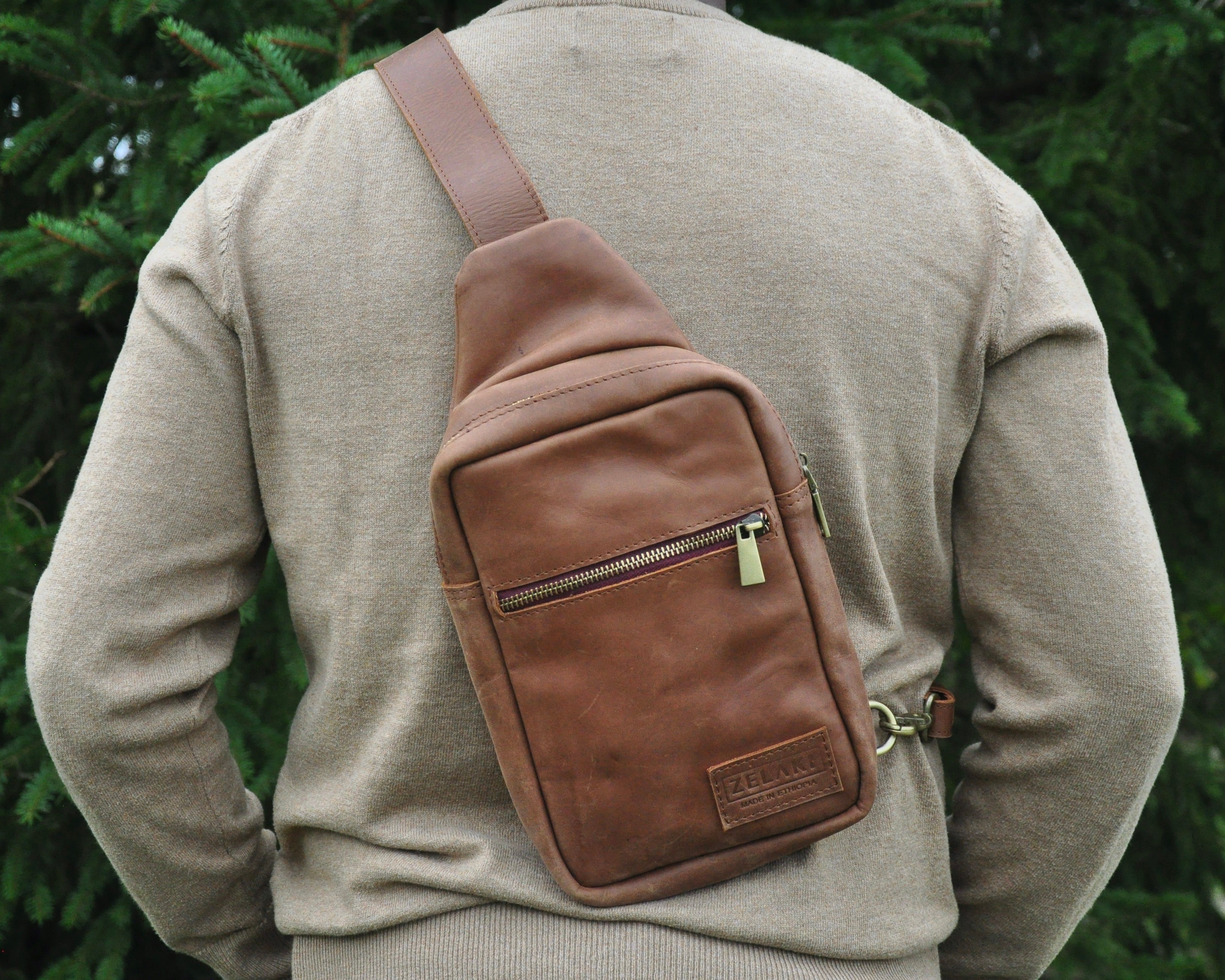 Full-grain Leather sling bag with multiple pockets, designed for versatile wear as a crossbody on your front or back, small to medium size in brown