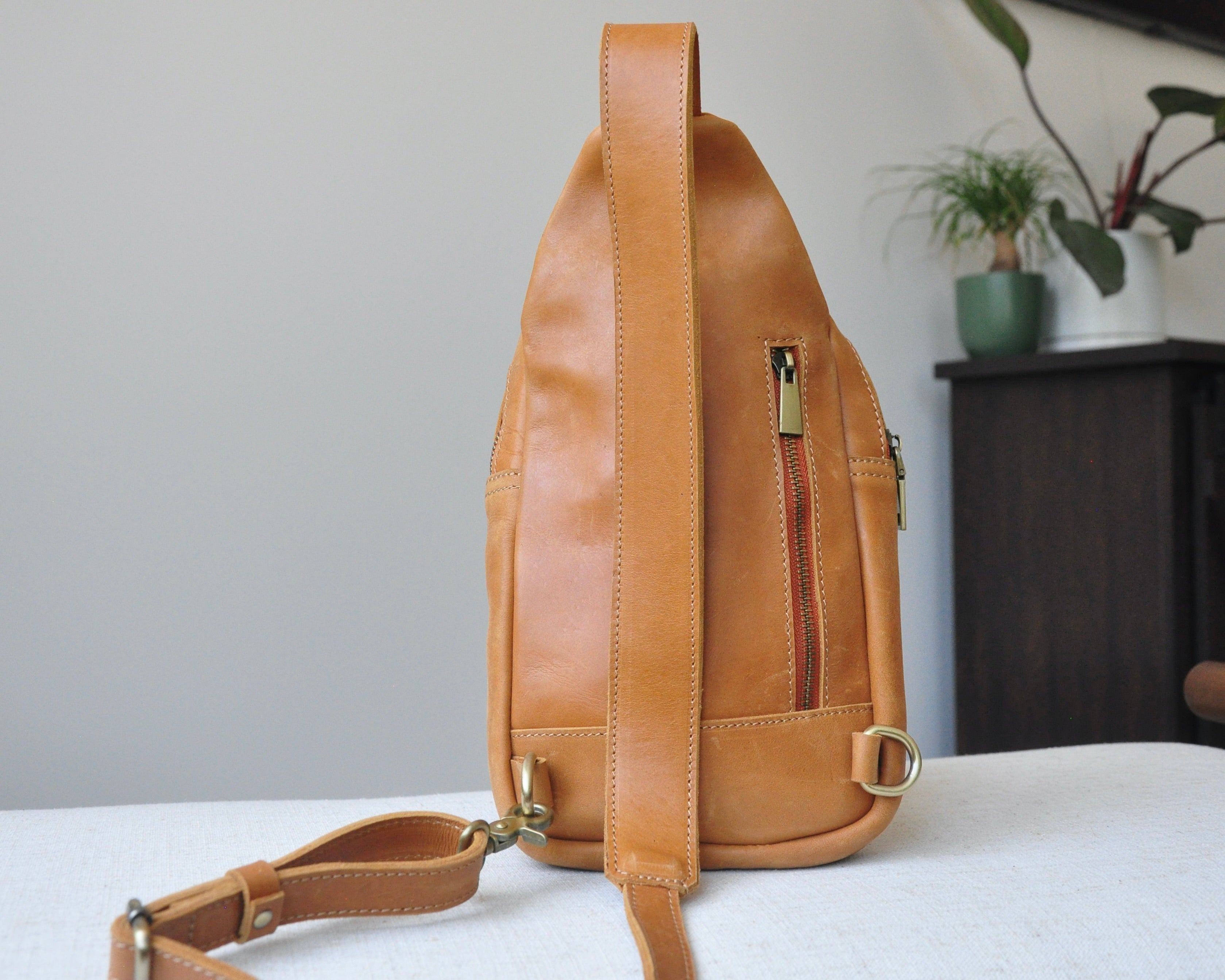 Full-grain Leather unisex sling bag with multiple pockets, designed for versatile wear as a crossbody on your front or back, small to medium size in brown