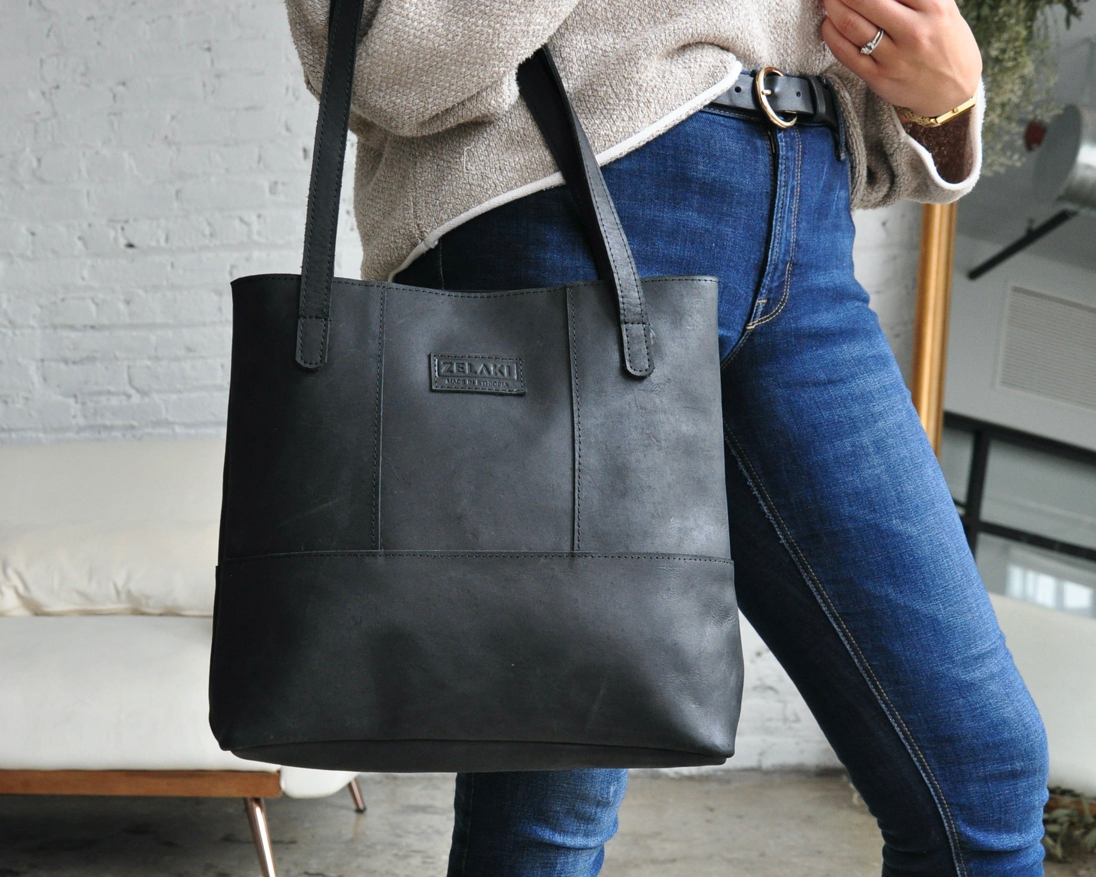 Large full-grain leather tote bag with minimalist design, featuring a zipper closure and an inside pocket in black