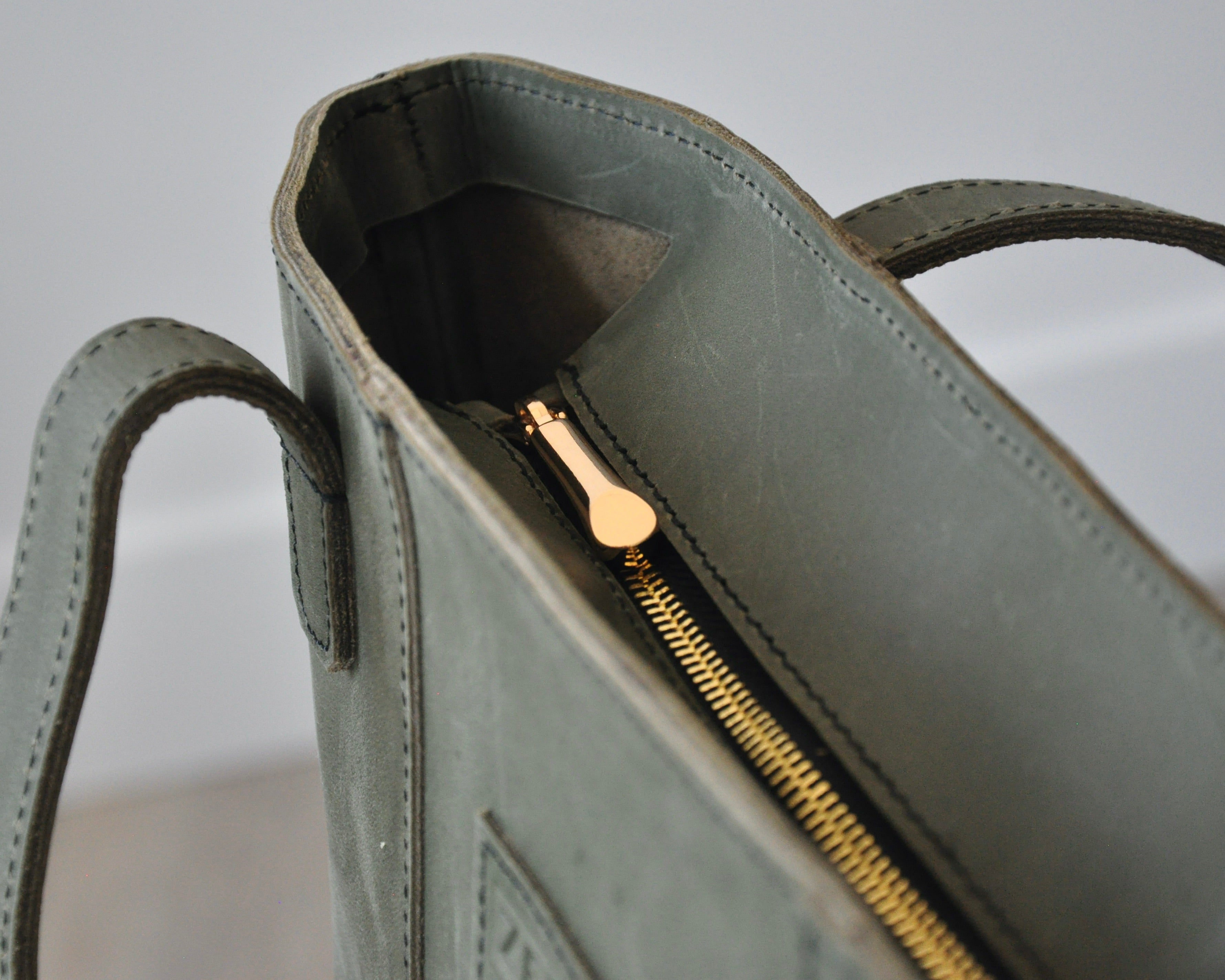 Large full-grain leather tote bag with minimalist design, featuring a zipper closure and an inside pocket in olive green