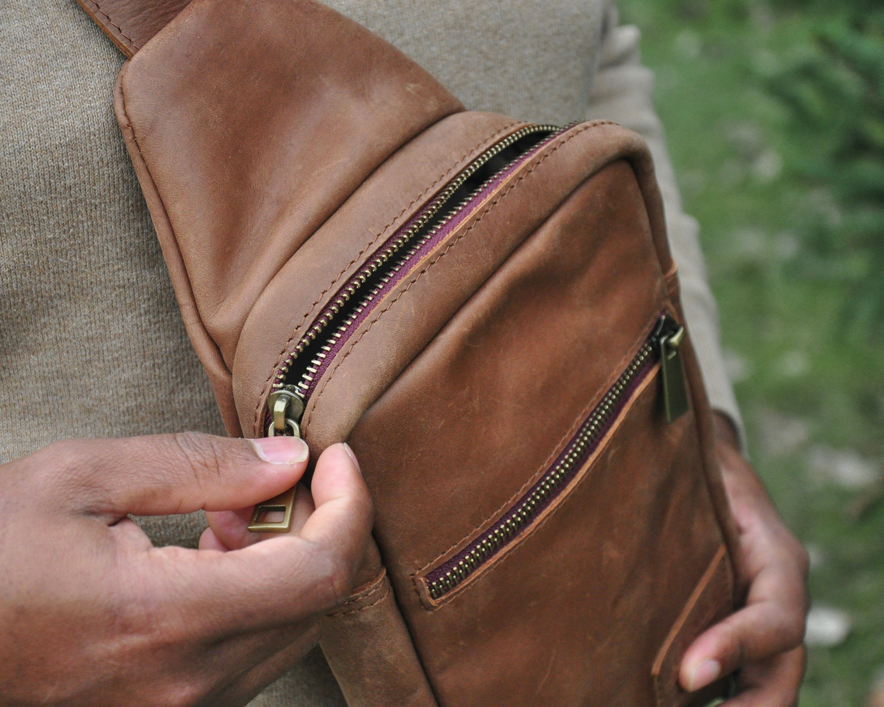 Full-grain Leather sling bag with multiple pockets, designed for versatile wear as a crossbody on your front or back, small to medium size in brown