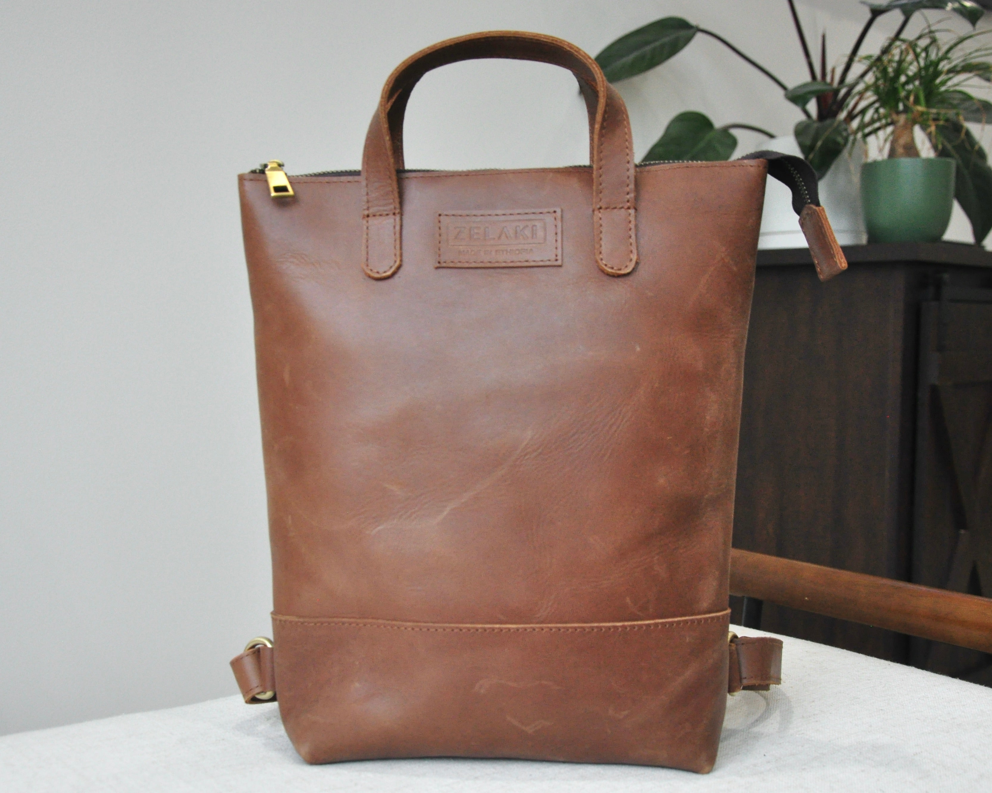 Small, brown, genuine full-grain leather backpack for women with zipper, durable and handmade in Ethiopia