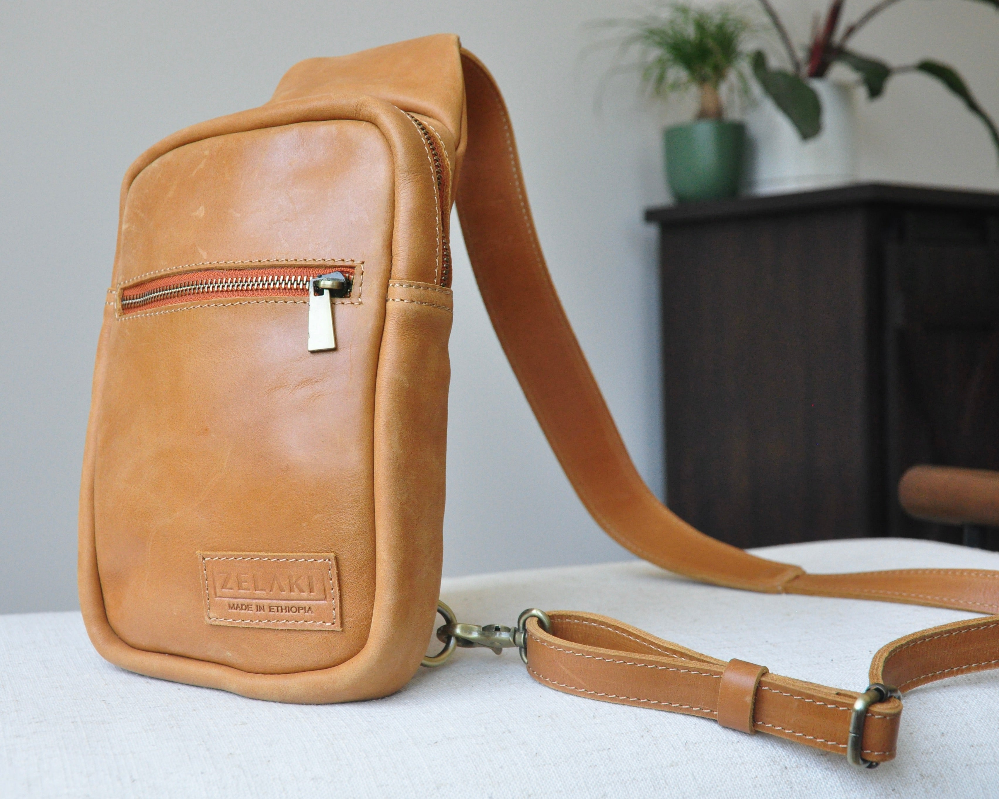 Full-grain Leather sling bag with multiple pockets, designed for versatile wear as a crossbody on your front or back, small to medium size in tan