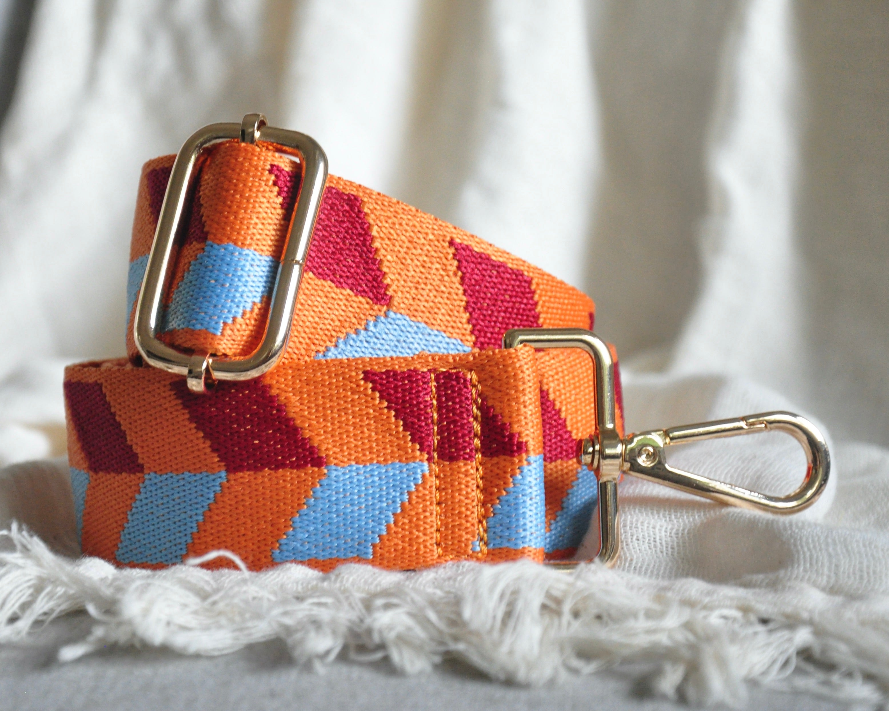 Geometric patterned adjustable crossbody strap in vibrant colors (orange, red, and blue) with gold hardware, perfect for customizing any purse or bag