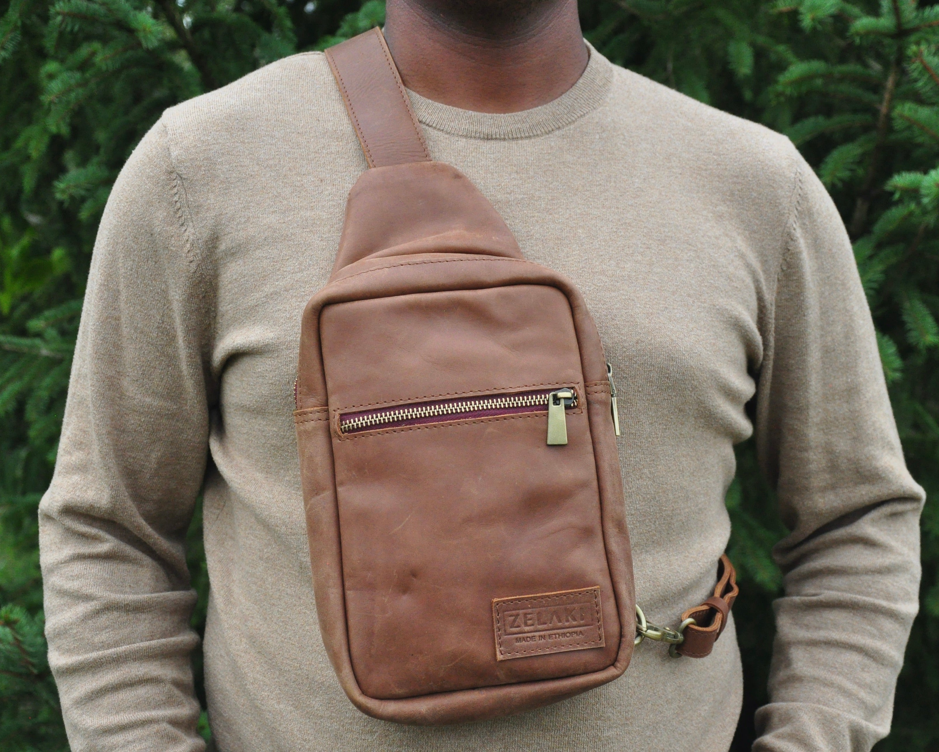 Full-grain Leather sling bag with multiple pockets, designed for versatile wear as a crossbody on your front or back, small to medium size in brown