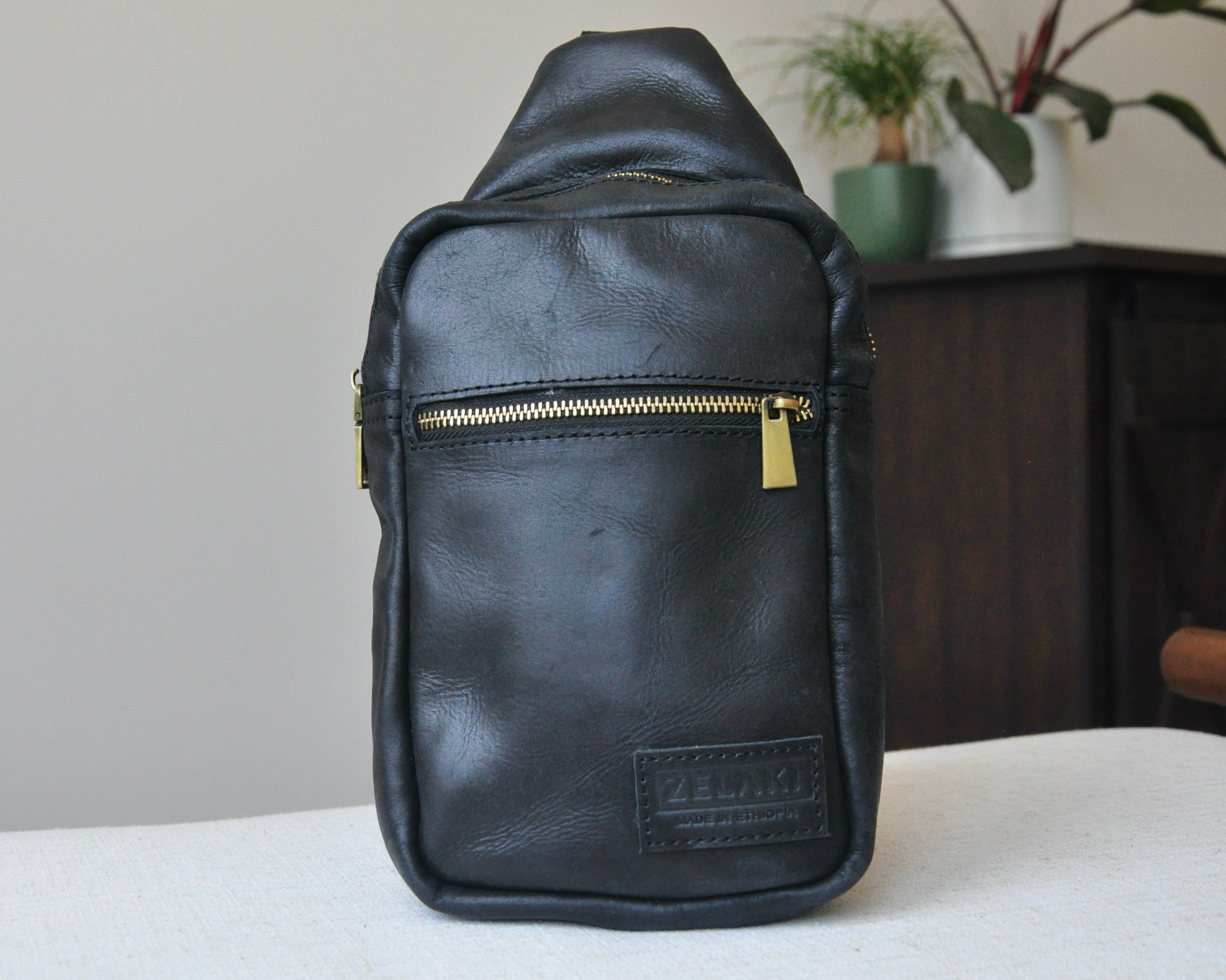Full-grain Leather unisex sling bag with multiple pockets, designed for versatile wear as a crossbody on your front or back, small to medium size in black