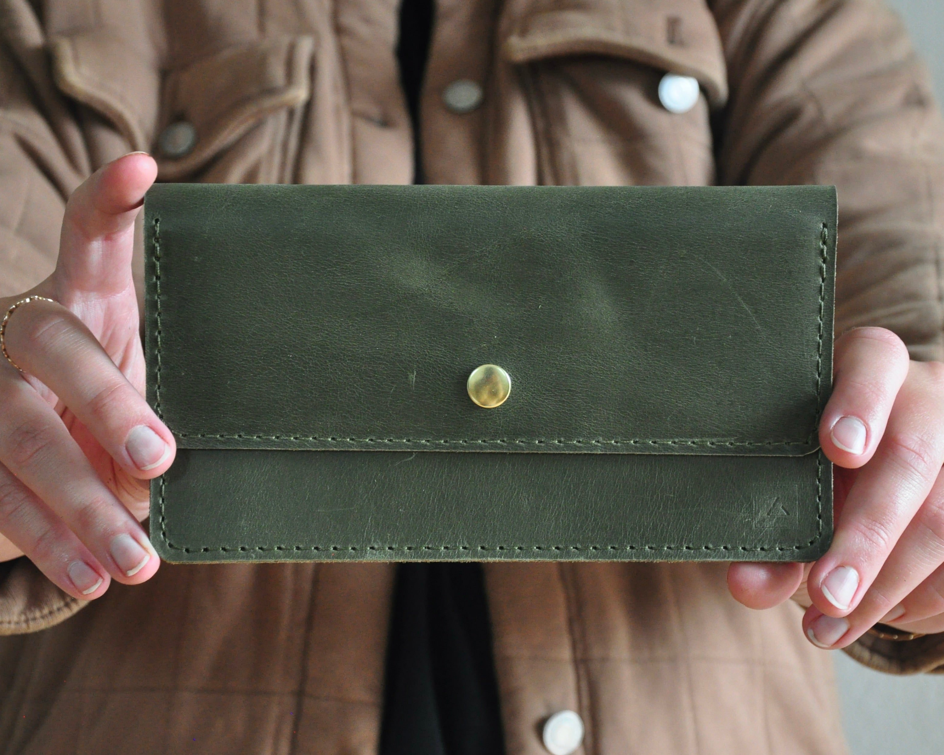 Picture of Olive green leather wallet being held as a small clutch