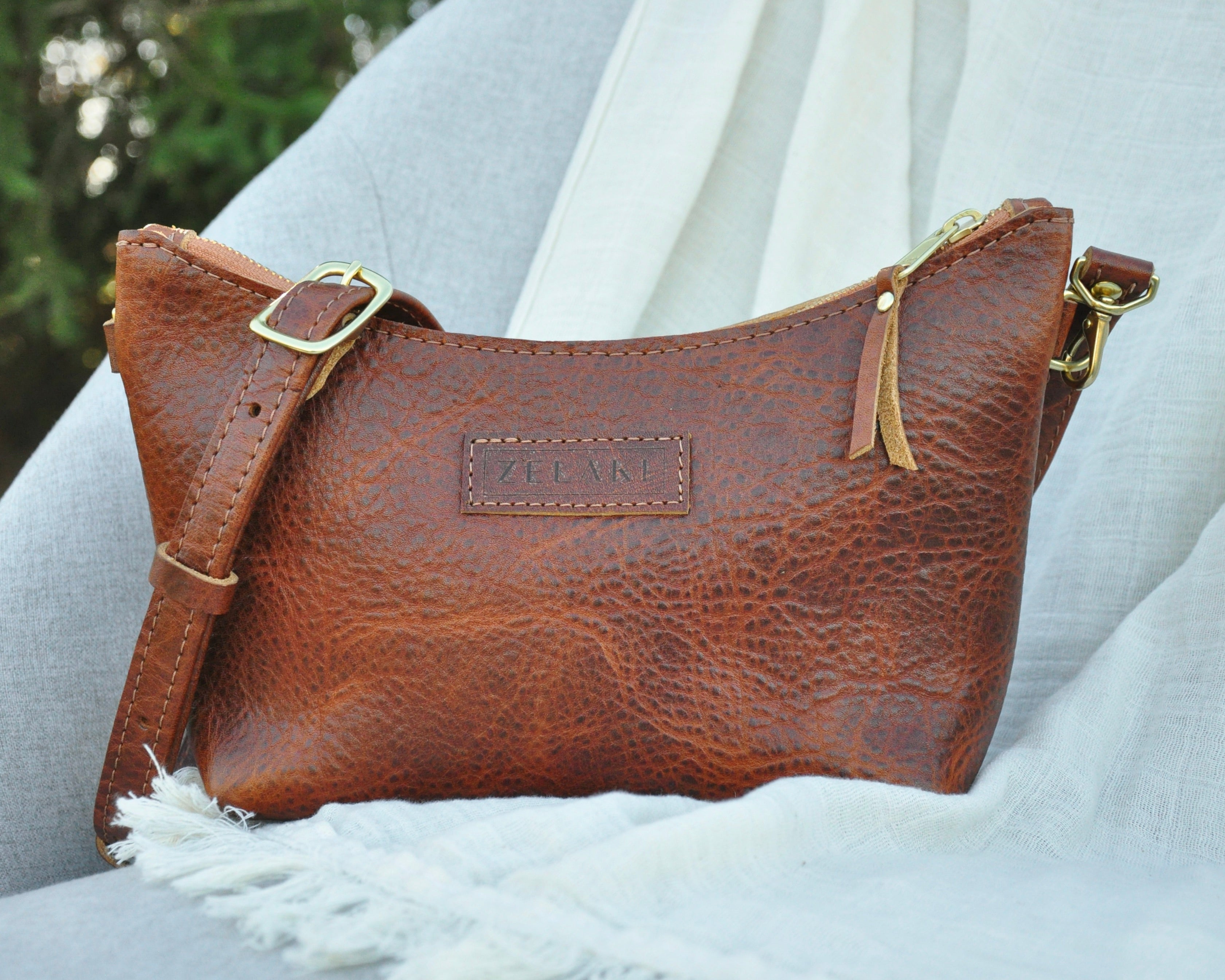 Brown leather handbag with gold accents on a light gray background